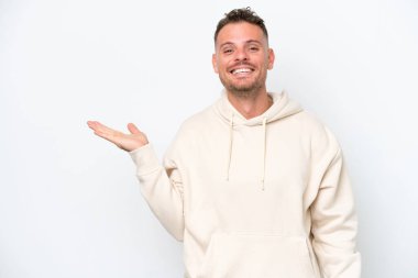 Beyaz arka planda izole edilmiş beyaz tenli yakışıklı bir adam, bir ilan vermek için avucunda hayali bir fotokopi makinesi tutuyor.