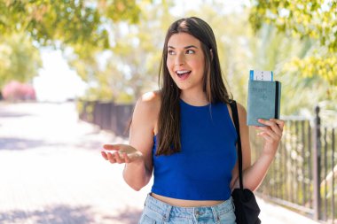 Genç, güzel Brezilyalı bir kadın, elinde sürpriz bir yüz ifadesiyle dışarıda bir pasaport tutuyor.