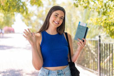 Genç, güzel Brezilyalı bir kadın elinde pasaport, elinde mutlu bir ifadeyle selamlıyor.