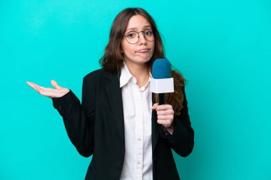 Genç TV sunucusu kadın, mavi arka planda izole edilmiş ve ellerini kaldırırken şüpheleri var.