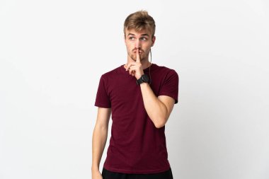 Beyaz arka planda izole edilmiş genç yakışıklı bir adam sessizlik işareti gösteriyor. Parmağını ağzına sokuyor.