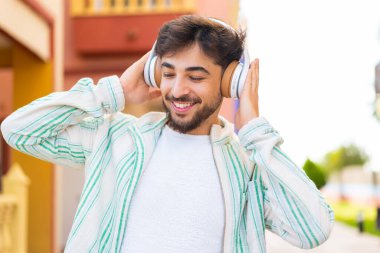 Açık havada müzik dinleyen yakışıklı bir Arap.