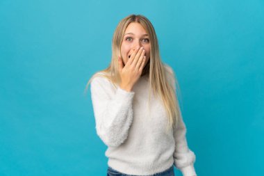 Mavi arka planda izole edilmiş genç sarışın kadın mutlu ve gülümsüyor.