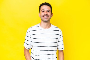 Genç yakışıklı adam, izole edilmiş sarı arka plan gülüyor.