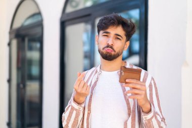 Dışarıdaki yakışıklı bir Arap 'ın elinde cüzdan ve hüzünlü bir ifadeyle