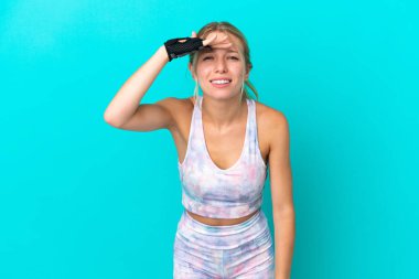 Sport caucasian woman isolated on blue background looking far away with hand to look something