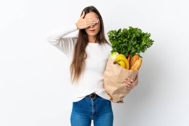 Young caucasian woman buying some food isolated on white background covering eyes by hands. Do not want to see something