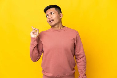Young Ecuadorian man isolated on yellow background intending to realizes the solution while lifting a finger up