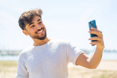 Yakışıklı bir Arap açık havada selfie çekiyor.