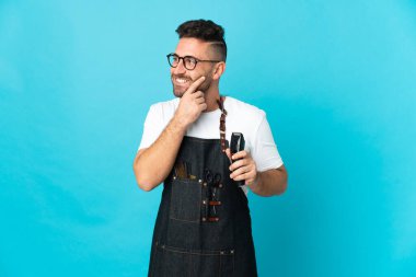 Önlüklü bir berber yukarı bakarken bir fikir düşünüyor.