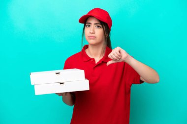 Pizza delivery woman with work uniform picking up pizza boxes isolated on blue background showing thumb down with negative expression