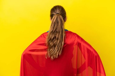Super Hero little girl isolated on yellow background in back position