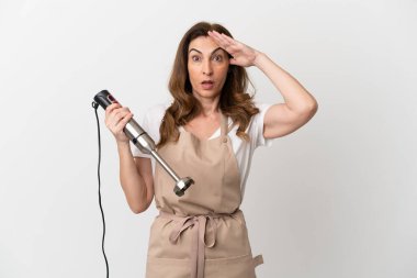 Middle aged caucasian woman using hand blender isolated on white background with surprise expression