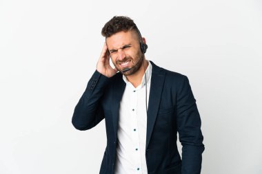 Tele pazarlamacı beyaz arka planda başağrısı olan bir kulaklıkla çalışıyor.