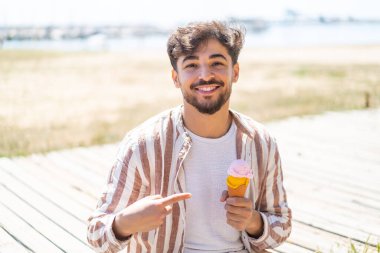 Handsome Arab man with a cornet ice cream at outdoors with surprise facial expression