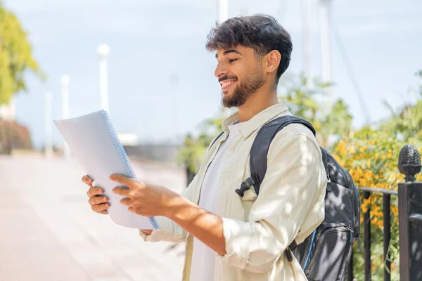 Genç bir Arap öğrenci açık havada neşeli bir ifadeyle.
