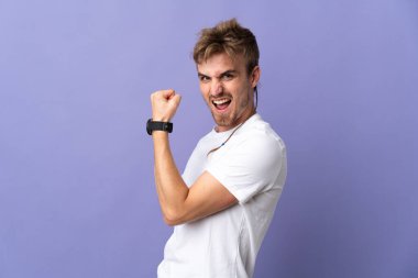 Mor arka planda izole genç sarışın adam zaferi kutluyor.