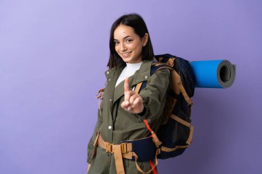 Young mountaineer woman with a big backpack over isolated background showing and lifting a finger