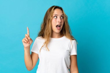 Mavi arka planda izole edilmiş genç sarışın kadın parmağını kaldırarak çözümü anlamaya çalışıyor.