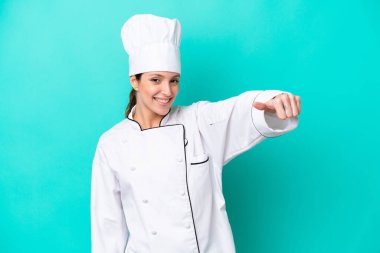 Kafkasyalı genç aşçı kadın mavi arka planda izole edilmiş bir şekilde baş parmak hareketi yapıyor.