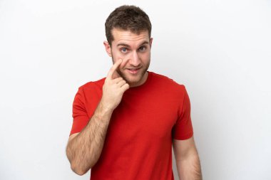 Beyaz arka planda izole edilmiş genç beyaz adam bir şey gösteriyor.