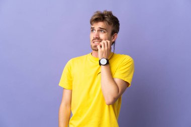 Young handsome blonde man isolated on purple background is a little bit nervous