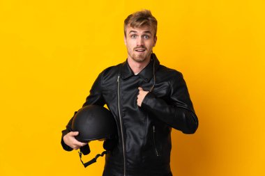 Motosiklet kasklı bir adam sarı arka planda izole edilmiş, şaşırmış bir yüz ifadesi var.