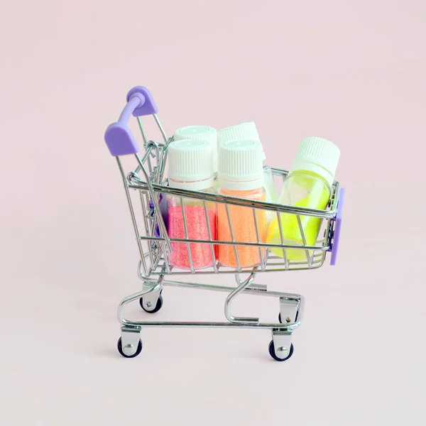 ショッピングカートは、マニキュアのための多色の明るい輝きを持つ多くの丸い瓶で満たされています。スパークリングスパンコール — ストック写真