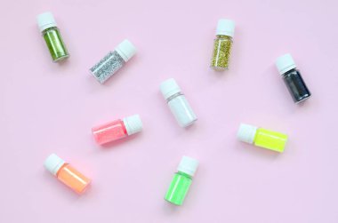 Renkli glitter şişeler ile düz bir yatıyordu desen pastel pembe arka plan yatıyor. Oje için çok renkli parlak ışıltılar ile birçok yuvarlak kavanoz. Köpüklü payetler. Üstte görüntü