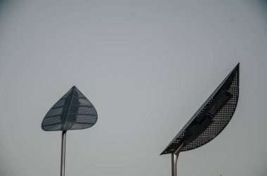 Gökyüzüne karşı yaprakları şeklinde metalden yapılmış yaratıcı modern sokak lambaları