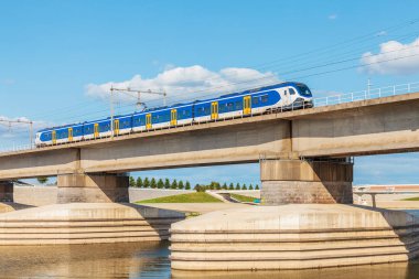 Hollanda treni Hollanda 'nın Nijmegen kentinin önündeki Waal nehrinin kenarından geçiyor.
