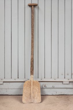 Bir fabrikada gri bir ahşap kapı karşı eski paslı kürek