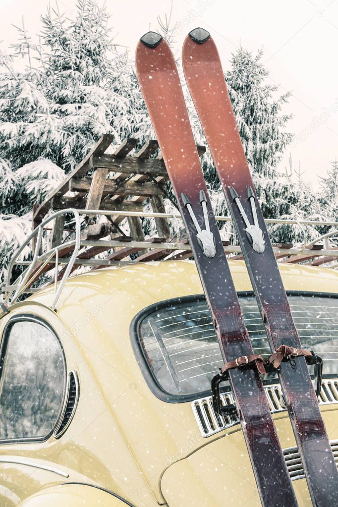 Classic car with vintage ski's and sled in winter during snowfall