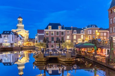 Hollanda 'nın Leiden, Hollanda' da su, teras, restoran ve tarihi binalarla dolu tarihi şehir merkezinin akşam manzarası