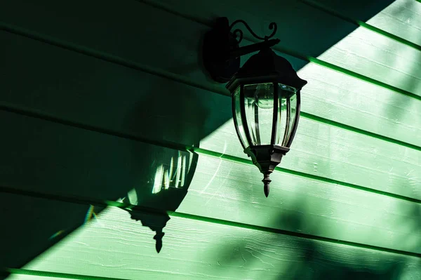 Электрическая лампа накаливания на зеленой деревянной стене — стоковое фото