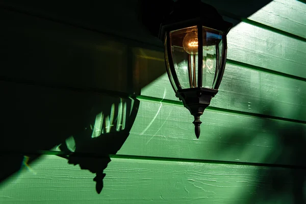 incandescent electric wall lamp on green wooden wall