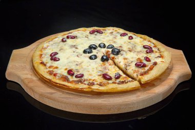 Pizza bir ahşap tepsi, siyah cam üzerinde.