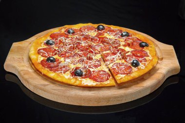 Pizza bir ahşap tepsi, siyah cam üzerinde.