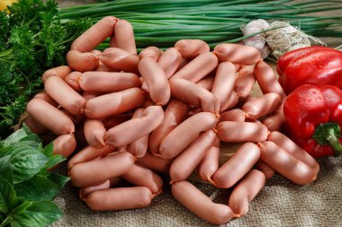 sosis bir ahşap masa, arka plan üzerinde sebze ve Yeşiller ile yatıyor