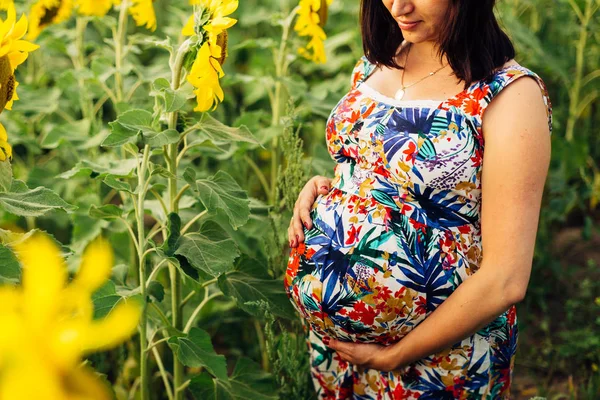 Grote foto van een zwangere vrouw in een veld met zonnebloemen — Stockfoto