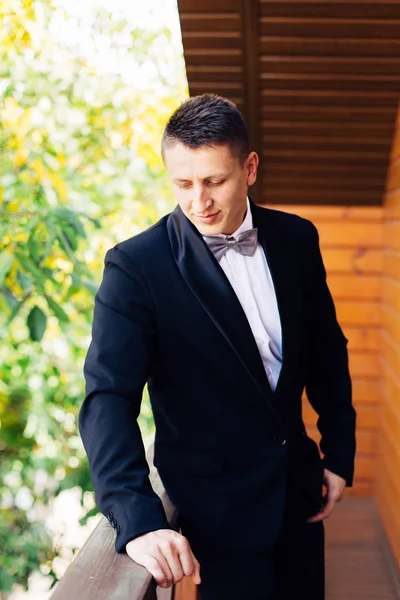 Portrait of a handsome groom in a black tuxedo with a bow-tie. — Stock Photo, Image
