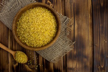 Bulgur kabuğu çıkarılmış tane rustik ahşap arka plan üzerinde kahverengi kase. Uzay kopyalayın. Üstten görünüm.