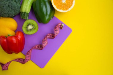 Sebze, meyve ve sarı zemin üzerine menekşe kesme tahtası üzerinde pembe santimetre. Üstten görünüm. Kopya alanı.