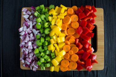 Kesme tahtası siyah ahşap zemin üzerine kıyılmış taze sebze. Üstten görünüm.