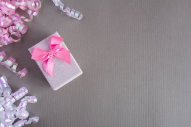 Gri arka plan üzerinde pembe Fiyonklu hediye paketi. Üstten görünüm. Kopya alanı.