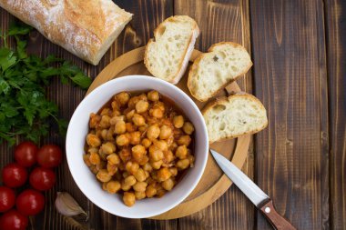 Nohut domates soslu beyaz kase ve baget ahşap arka plan üzerinde. Üstten görünüm. Kopya alanı.