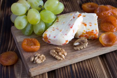Ahşap kesme tahtası üzerinde kuru kayısı ile yumuşak peynir