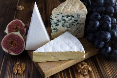 Peynirler, üzüm ve incir kahverengi ahşap zemin üzerinde