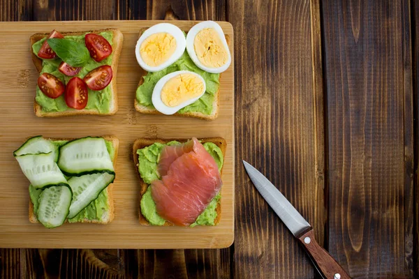 Stock image Sandwiches with avocado and different ingredients on the brown  wooden background.Top view.Copy space.