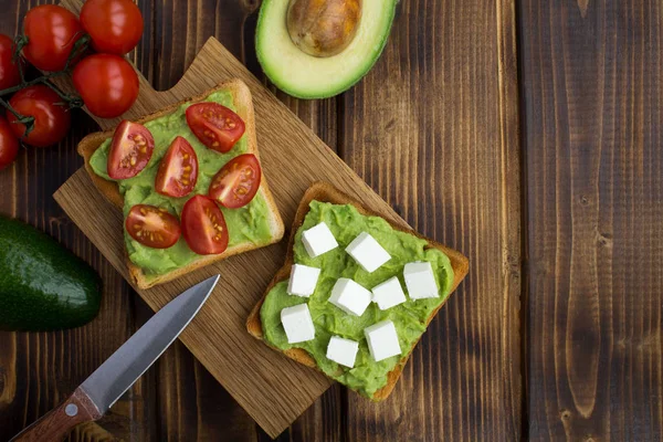 Vejetaryen sandviç kahverengi ahşap zemin üzerinde avokado, kiraz ve yumuşak peynir ile. Üstten görünüm. Kopya alanı.